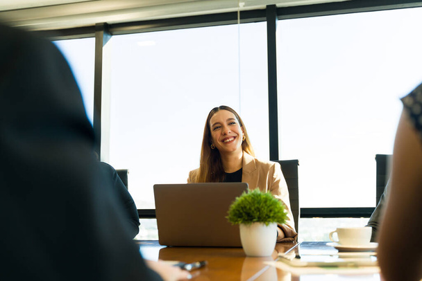 Mooie blanke zakenvrouw is vriendelijk en glimlachend tijdens het deelnemen aan een zakelijke bijeenkomst - Foto, afbeelding