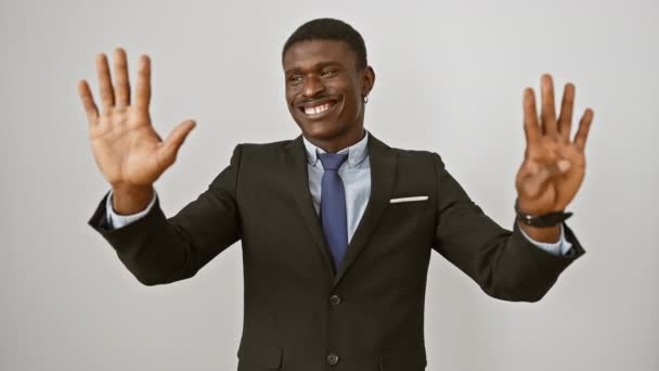 Веселий афроамериканський чоловік у костюмі стоїть ізольовано, піднімаючи пальці вгору, показуючи номер 9 з щасливою посмішкою на білому тлі - Кадри, відео