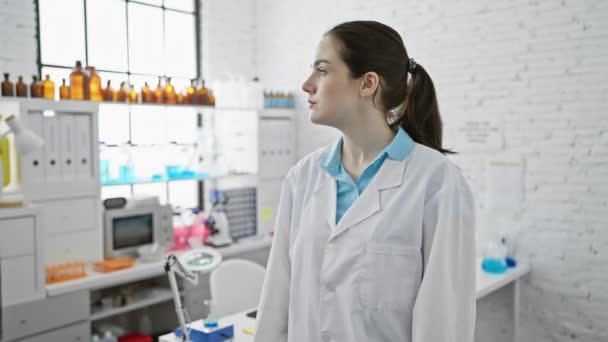 Γυναίκα με αυτοπεποίθηση επιστήμονας με εργαστηριακή ποδιά, στέκεται σε ένα σύγχρονο εργαστήριο με σταυρωμένα χέρια. - Πλάνα, βίντεο