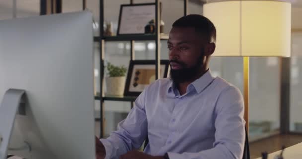 Zwarte zakenman, gezicht door laptop op kantoor en gelukkige professional en technologie 's nachts op het werk. Afrikaanse persoon, portret en positief in carrière als accountant en vertrouwen in het opstarten door de computer. - Video