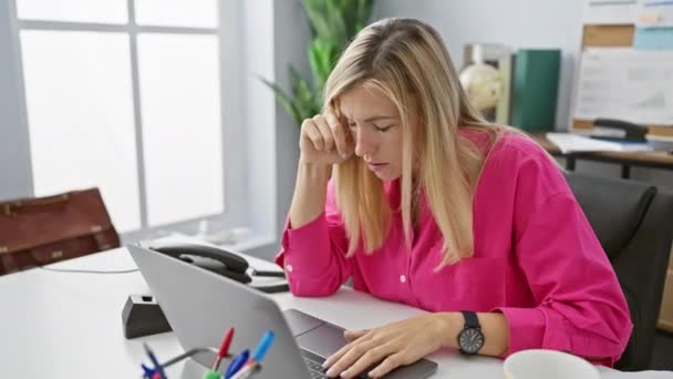 Stressaantunut nuori nainen työskentelee kannettavan nykyaikaisessa toimistossa, osoittaa väsymystä ja päänsärkyä - Materiaali, video
