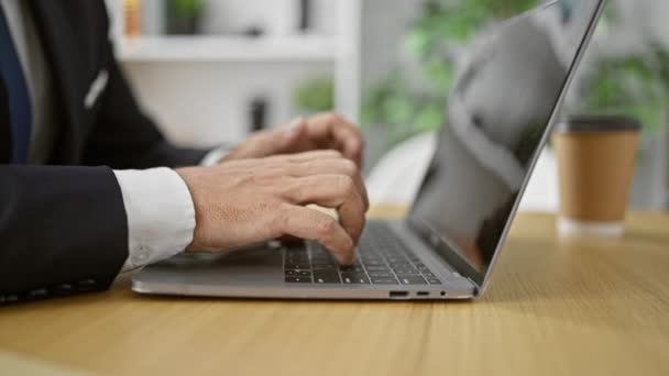 Energiczny młody Latynos, siwy i przystojny, umiejętnie piszący na laptopie w tętniącym życiem biurze. oddany pracownik wykazujący prawdziwą sprawność biznesową w pomieszczeniach. - Materiał filmowy, wideo