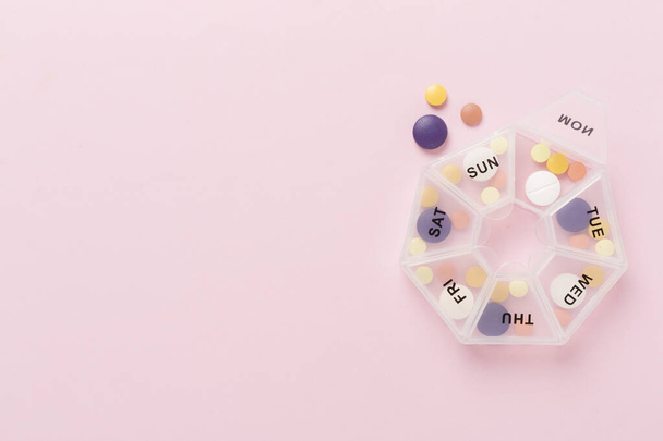 Dagelijkse pil doos met medicijnen op kleur achtergrond, bovenaanzicht - Foto, afbeelding