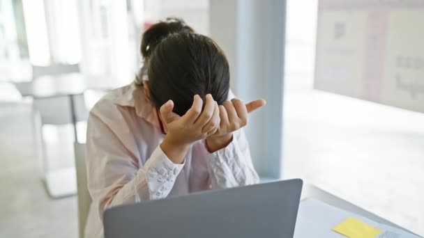 Stres hispánská žena s brýlemi v kanceláři pocit ohromena prací, hlavu v rukou na svém notebooku. - Záběry, video
