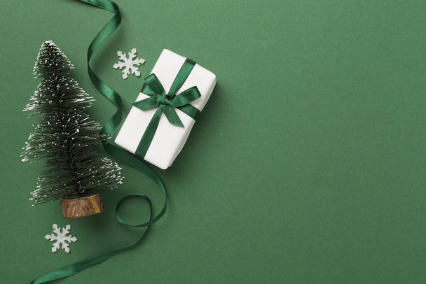 Miniatuur kerstboom met geschenkdozen en decor op kleur achtergrond - Foto, afbeelding