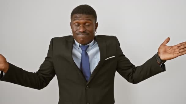 Onnozele maar knappe Afro-Amerikaanse man in pak, verward met opgeheven armen - echte verbijstering over geïsoleerde witte achtergrond - Video