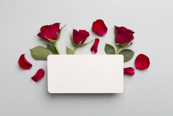 Greeting card mockup with red roses on color background, top view - Foto, Bild