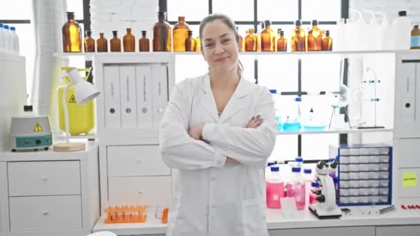 Magabiztos, kék szemű fiatal nő, keresztbe tett karokkal a laboratóriumban. boldog, mosolygós, és pozitívan néz ki, hogy öröm neki laboratóriumi munka - Felvétel, videó