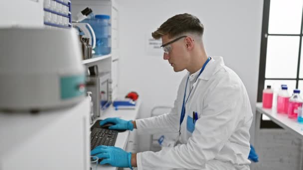 Väsynyt nuori valkoihoinen mies tiedemies, joka venyy taaksepäin kirjoittaessaan tärkeitä tietoja, peitti käsineet vilkkaassa laboratoriohuoneessa. - Materiaali, video