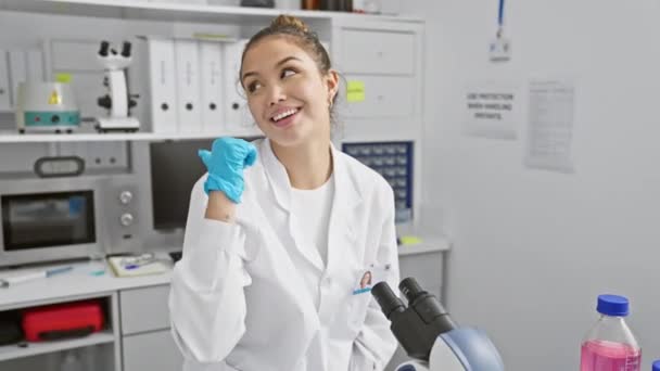 Χαρούμενη νεαρή Ισπανίδα επιστήμονας με στολή, με ανοιχτό το στόμα χαμογελάει στο εργαστήριο. - Πλάνα, βίντεο