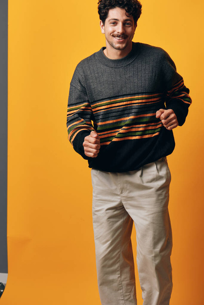 Άνθρωπος χαμόγελο φοιτητής μοντέλο πορτρέτο τύπος γενειάδα πουλόβερ στούντιο φόντο σύγχρονο καυκάσιος αρσενικό δροσερό πορτοκαλί μοντέρνα σοβαρά χαρούμενος νεαρός ενήλικας σκέφτεται φυσική μόδα - Φωτογραφία, εικόνα