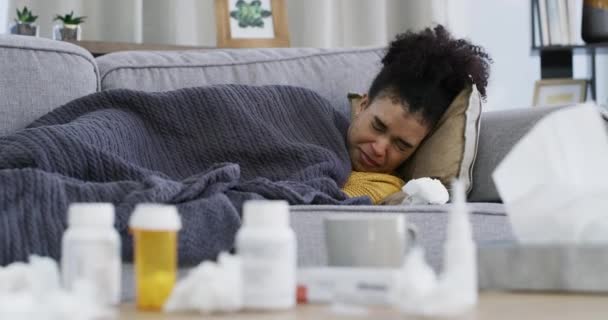 Γυναίκα, φυσάει μύτη ή ιστό στον καναπέ ως άρρωστο, ανάρρωση ή αλλεργίες γρίπης στο διαμέρισμα με φάρμακα. Βραζιλιάνος άνθρωπος, κρύο ή φτάρνισμα σε ανάπαυση σε καναπέ, χάπια μπουκάλια ή πυρετό στο σαλόνι στο σπίτι. - Πλάνα, βίντεο