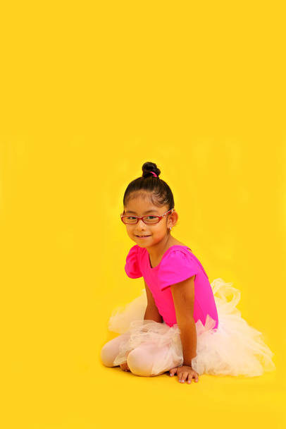 4-jarige brunette Latina meisje met bril gekleed in roze maillot en ballerina tutu neemt ballet lessen als therapie voor haar autisme en ADHD - Foto, afbeelding