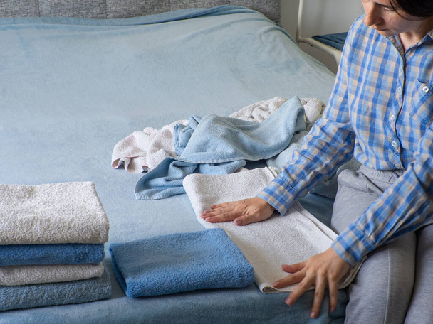 Mujer plegable toalla de rizo limpio en el dormitorio. Organizar la colada en casa. Toalla después del lavado. Concepto de minimalismo estilo de vida y sistema de plegado japonés. Armario ordenado. - Foto, Imagen