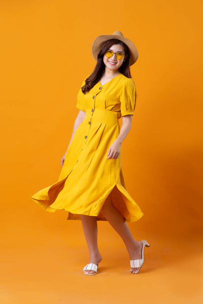 portrait of beautiful asian girl wearing yellow dress on orange background - Photo, Image