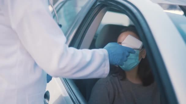 Nurse, car driver and woman with thermometer to check temperature for medical screening, disease control or travel protocol. Drive through, infrared scanner and doctor show test results to patient. - Footage, Video