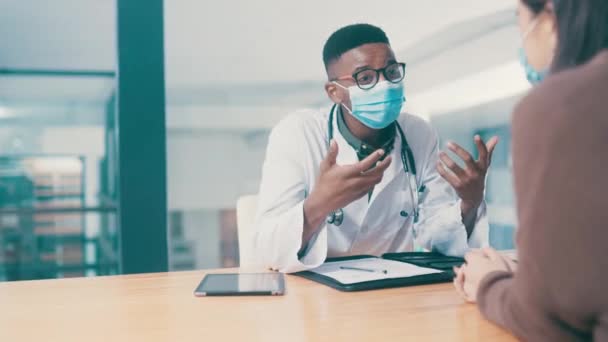 Black man, doctor and patient with healthcare, medical advice or conversation with diagnosis, help or speaking. African person, mask or office with wellness, talking or consultation with professional. - Footage, Video