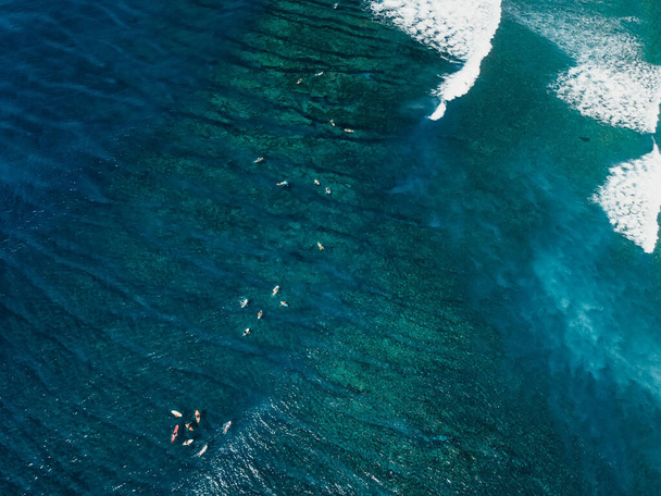 Widok z lotu ptaka z surferami i falami surfingowymi w czystym błękitnym oceanie - Zdjęcie, obraz