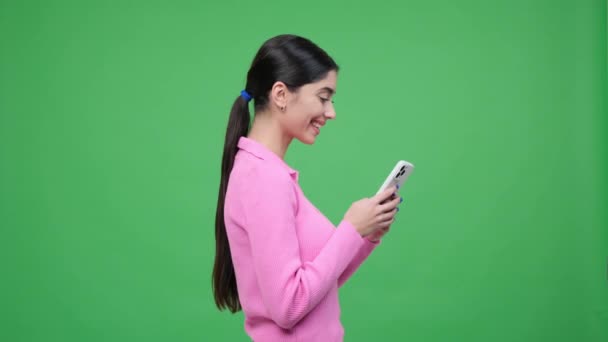 Profilo ritratto su sfondo verde cattura una donna caucasica ridente con un telefono, irradiando gioia e divertimento, pieno del calore di risate genuine ed energia positiva. - Filmati, video