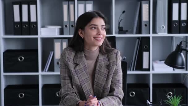 Cheerful Caucasian businesswoman gazes into the camera in the office. This image captures the approachable and friendly demeanor she embodies, fostering a positive and engaging atmosphere. - Footage, Video