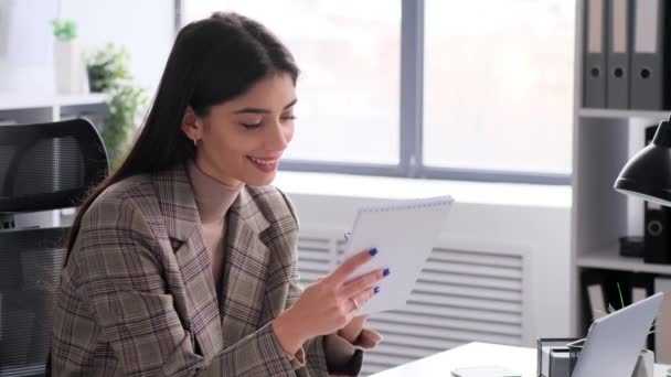 Content businesswoman diligently performs tasks in the office while writing in notebook. This image encapsulates the positive and productive atmosphere she contributes to the professional setting. - Footage, Video