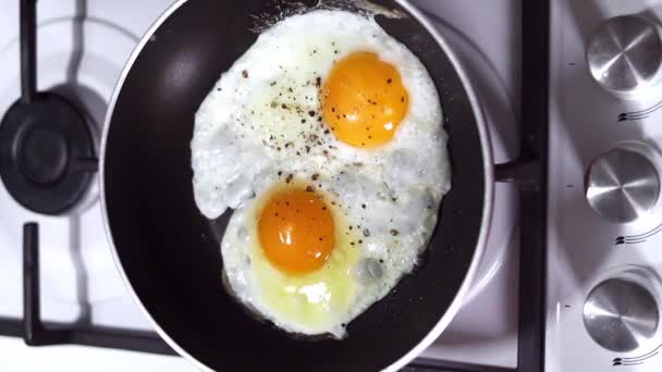 Δύο αυγά κοτόπουλου τηγανίζονται σε ένα κοντινό τηγάνι. Έννοια πρωινού. - Πλάνα, βίντεο