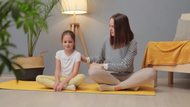 Healthy body, happy child. Home activities for fitness. Children's active lifestyle. Young mother and her charming little daughter doing yoga together at home - Séquence, vidéo
