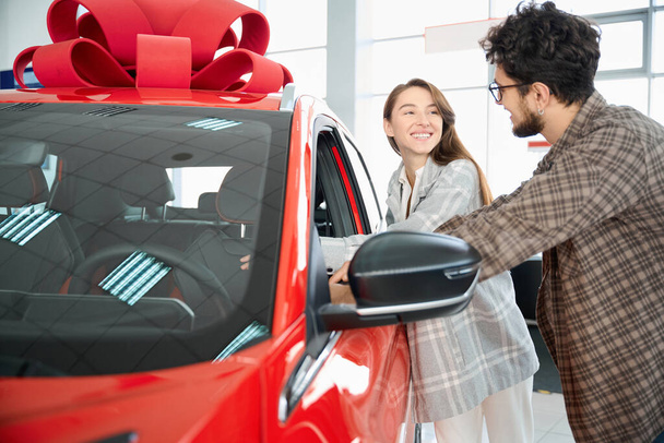 Alegre hombre y mujer posando en concesionario de automóviles y elegir el color del futuro coche - Foto, Imagen
