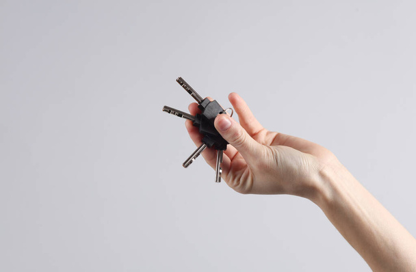 Manojo de llaves en mano femenina sobre fondo gris - Foto, Imagen