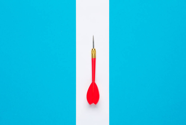 Piros darts, kék háttérrel, fehér csíkkal. Kreatív elrendezés, minimalizmus - Fotó, kép