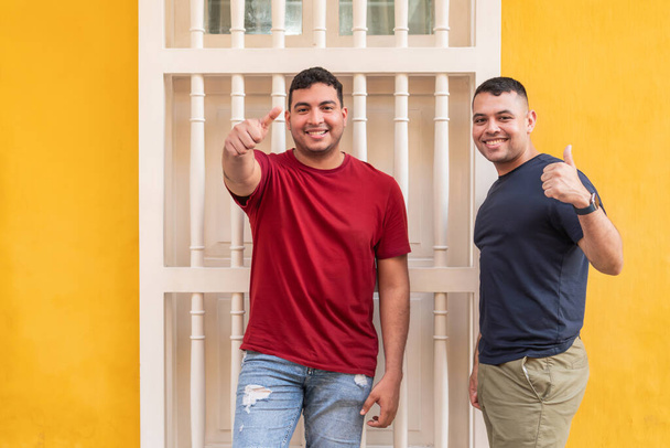 Twee vrolijke mannen die duimen geven in een stedelijke omgeving - Foto, afbeelding
