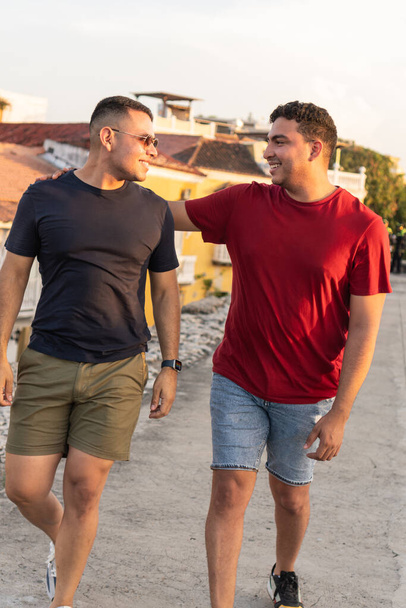 Hombres latinos caminando y disfrutando de una conversación en una azotea al atardecer - Foto, imagen