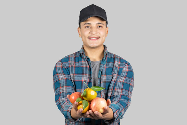 Молодой азиатский мышечный и здоровый мужчина фермер продвигает органический образ жизни с фруктами и фруктовой корзиной - Фото, изображение