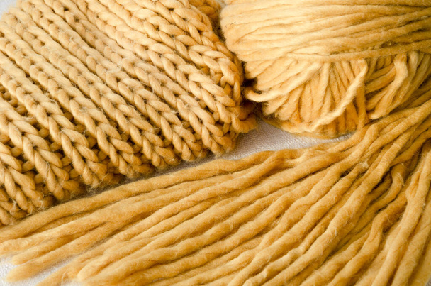 Breien, sjaal en bal van geel garen. Synthetische vezels, driedimensionaal patroon. - Foto, afbeelding