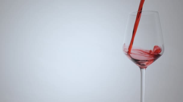 Víno nalévání ve sklenici vína na bílém pozadí. Detailní záběr. - Záběry, video