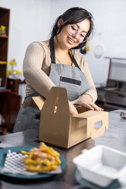 takeaway burger packaging, fast food ready for delivery, customer service and restaurant lifestyle, woman in restaurant working - Photo, Image