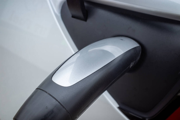 A nova era do transporte. Uma visão de close-up da alça de um carregador elétrico firmemente conectado a um carro. - Foto, Imagem