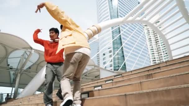 Groupe hipster divers marchant jusqu'à l'escalier tout en effectuant la danse de rue. Jolie danseuse asiatique dansant avec un ami multiculturel à la ville. Style libre, style de vie. Sport de plein air 2024. Brillamment. - Séquence, vidéo