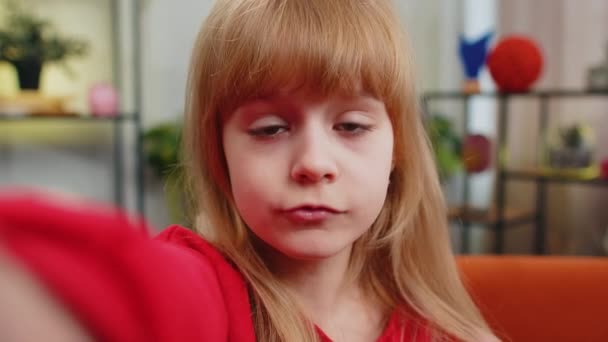 POV einer kaukasischen Kinderbloggerin, die ein Selfie auf ihrem Smartphone macht und online mit Abonnenten der sozialen Medien kommuniziert. Weibliche Teenager-Kind Aufnahme Video-Geschichte zu Hause in Zimmer sitzt auf Couch - Filmmaterial, Video
