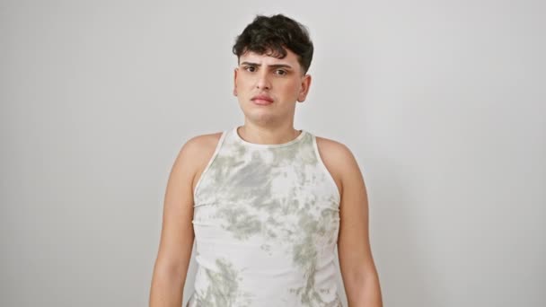 Μπερδεμένος νεαρός γκέι άντρας με αμάνικο μπλουζάκι, να στέκεται απέναντι σε απομονωμένο λευκό τοίχο, να δείχνει σκεπτικός και σαρκαστικός με ανοιχτό στόμα και μπερδεμένο πρόσωπο - Πλάνα, βίντεο
