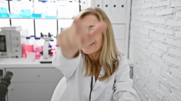 Mérges szőke tudós középkorú, dühös és frusztrált, elégedetlen és rád mutat a labor belső kamerájából. - Felvétel, videó