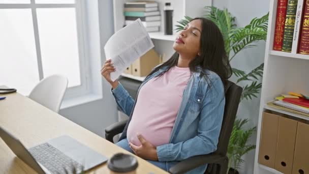Mladá těhotná obchodní žena, bojuje s nepohodlím z horké kanceláře, uchýlit se k používání dokumentů jako ruční ventilátor, zatímco ponořena do náročné práce. - Záběry, video