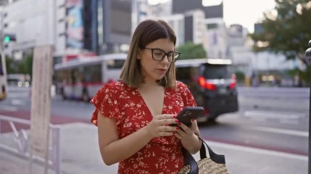 Όμορφη ισπανόφωνη γυναίκα με γυαλιά σε tokyo, ψηφιακή σύνδεση μέσω smartphone στους δρόμους της πόλης - Πλάνα, βίντεο