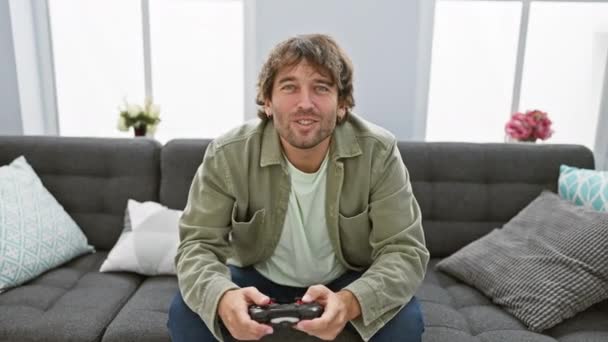 Onnellinen valkoihoinen mies gamer pelaa konsolia nykyaikaisessa olohuoneessa. - Materiaali, video