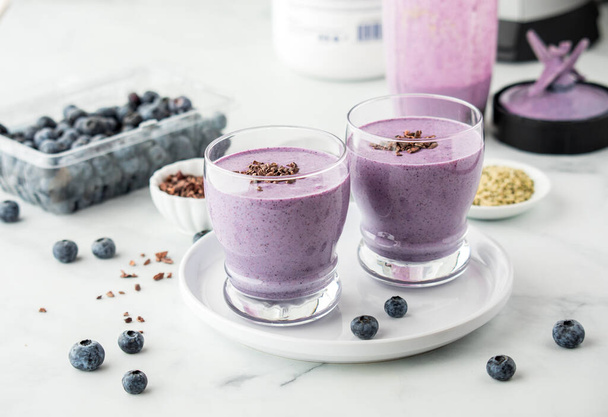 Glasses of fresh blueberry protein smoothies topped with cacao nibs, ready for drinking. - Photo, Image