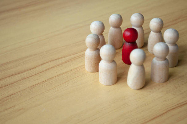 Rode houten pop omringd door andere poppen. Vertegenwoordigen van discussie, leiderschap of intimidatie. - Foto, afbeelding