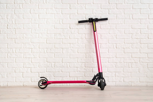 Pink modern electric kick scooter near white brick wall - Photo, Image