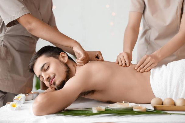 Mladý muž dostává masáž od terapeutů v lázeňském salonu - Fotografie, Obrázek