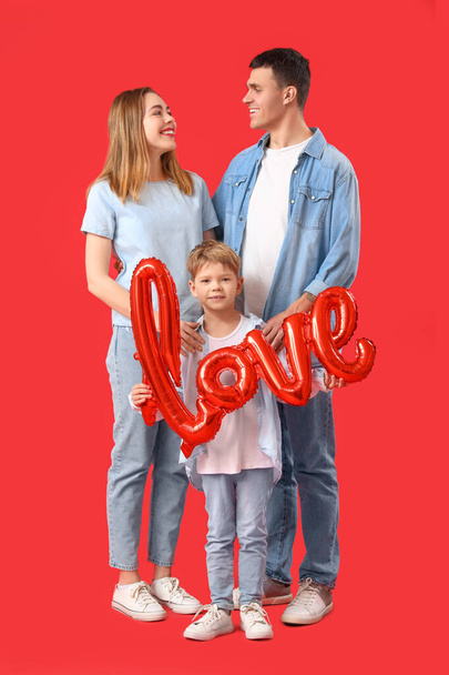 Kleiner Junge mit Wortliebe aus Luftballons und seinen Eltern auf rotem Hintergrund. Valentinstag-Feier - Foto, Bild