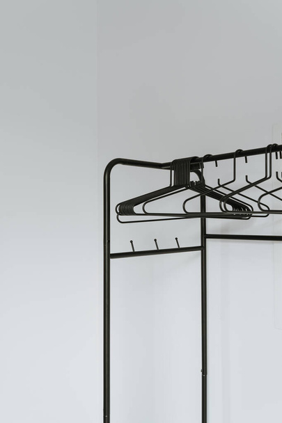 Leere Kleiderbügel am Boden hängen über der weißen Wand. Minimalistisches Wohnkonzept mit Garderobe. Online-Modegeschäft, Online-Shop Hintergrund - Foto, Bild